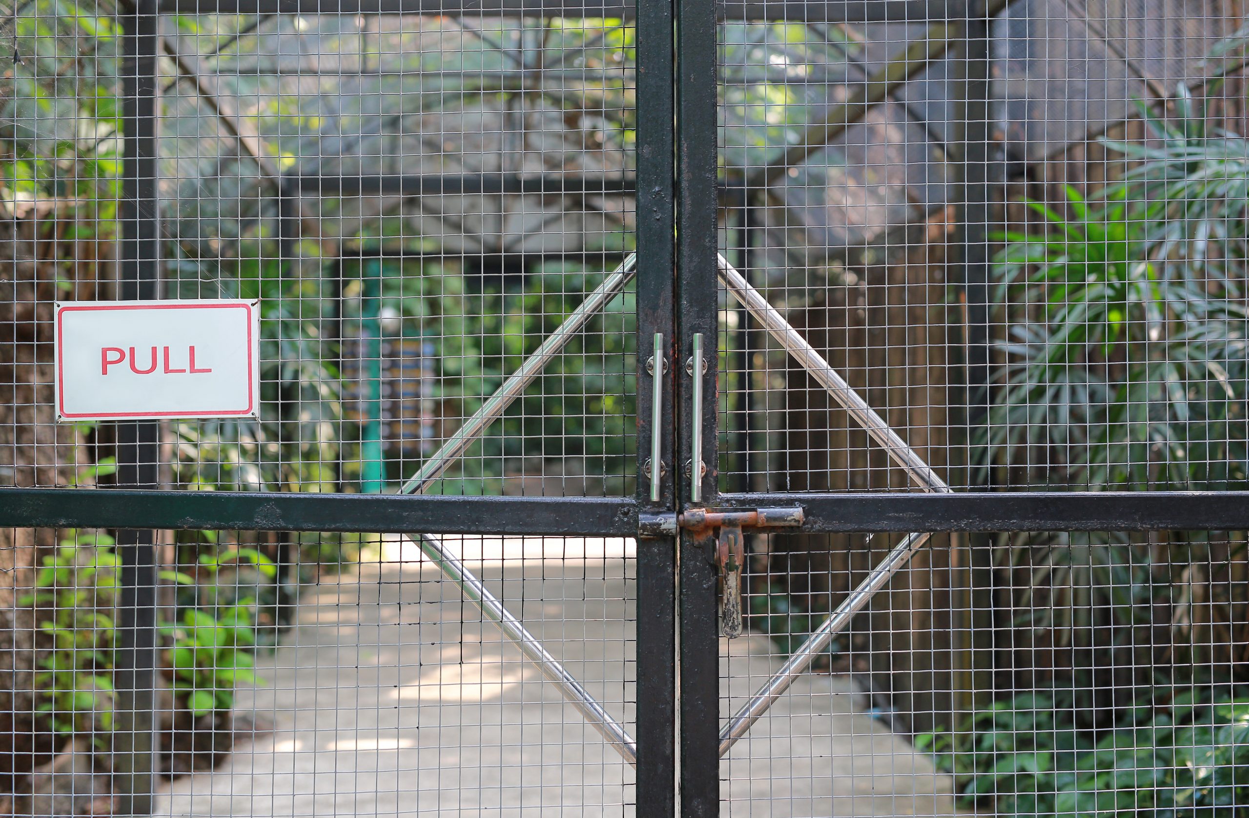 Iron cage door in zoo with "PULL" label.