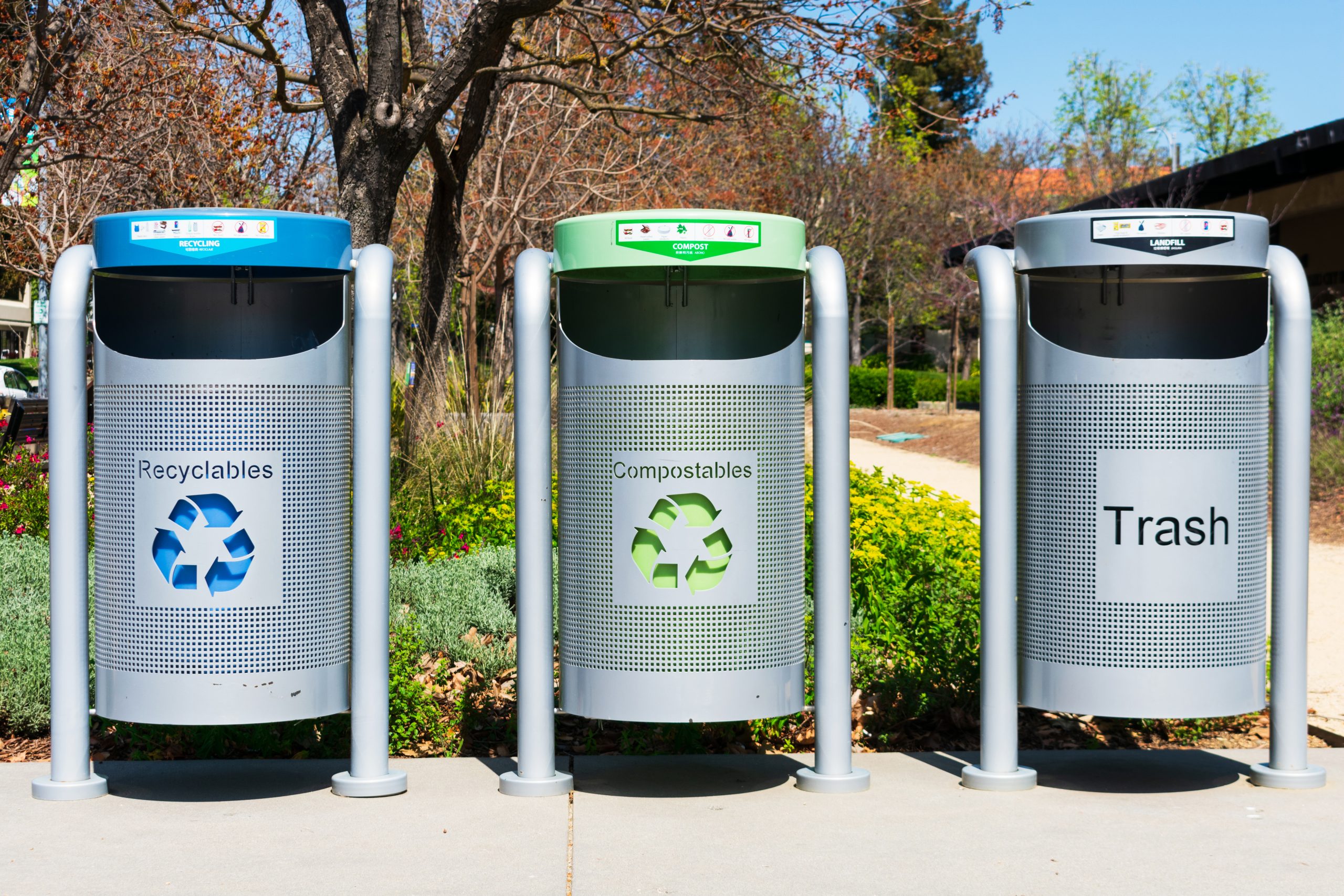 Modern multi color bins to collect recyclables, compostables and trash set up outdoor in public place